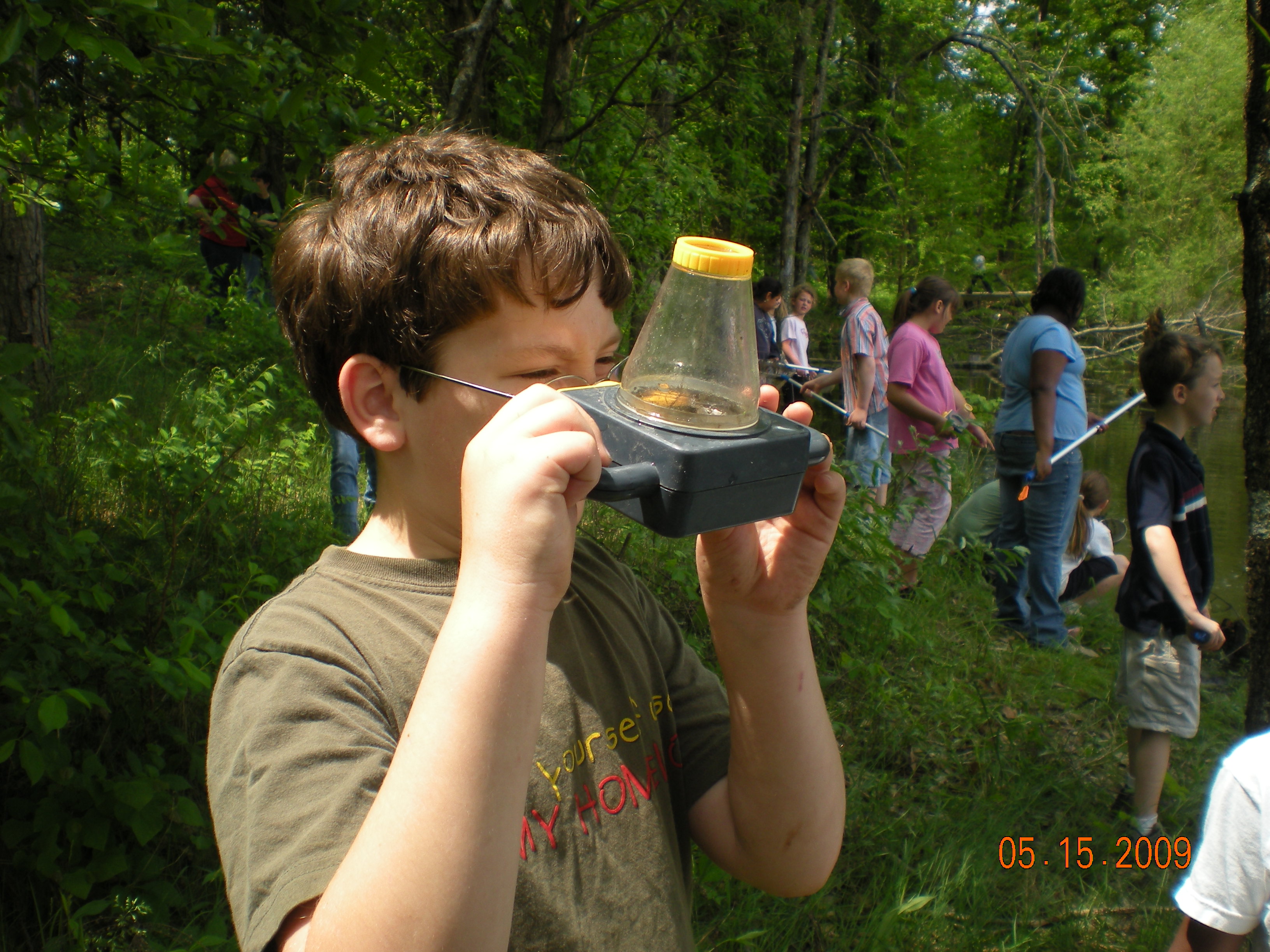 Hawthorne Elementary 3rd Grade student using an observation container to explore the pond
